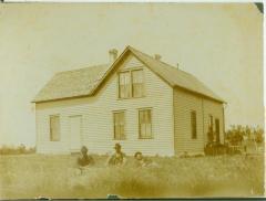 Three men sitting in the grass in front of a house