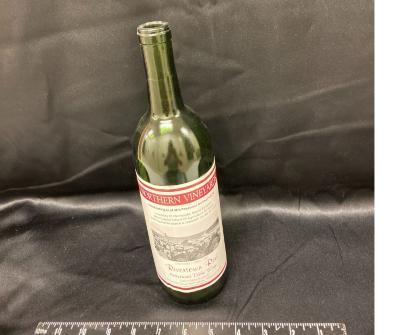wine bottle with UMM label celebrating the anniversary of 90 years of the West Central School of Agriculture and 40 years of the University of Minnesota Morris, fall 2000. Wine name, Rivertown Red, American Table Wine, green bottle  with white and maroon label.