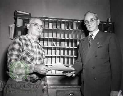 Lloyd Neel Retires from Villard, Minnesota Postal Service, Postmaster Neil Hopkins presents certificate.