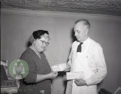 Harry Anderson, Mrs. Ray Overmire admire Quaker Oats Checks. Glenwood, Minnesota