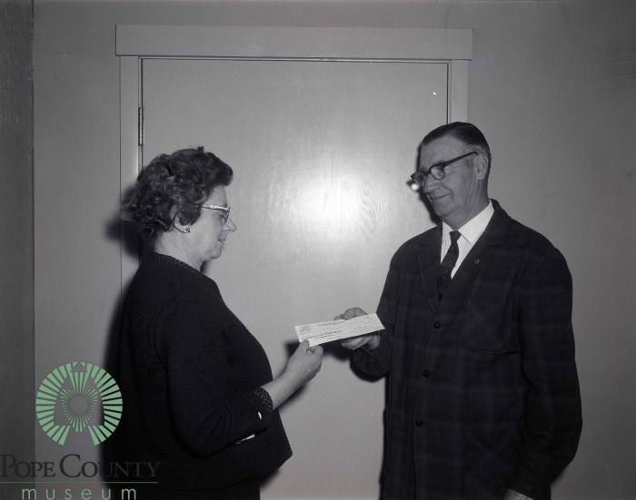 L. F. Gasser Giving a 550 dollar check to Mabel Barsness.