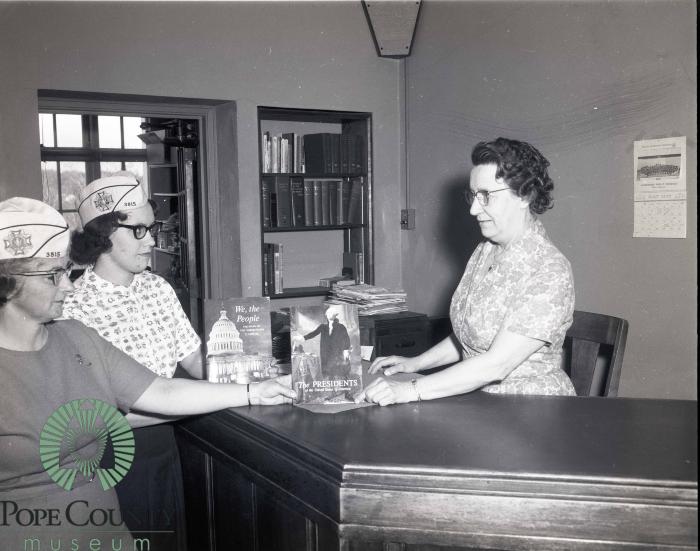 Carol Dokken and Donna Hagen giving Books to Kathryn Nelson