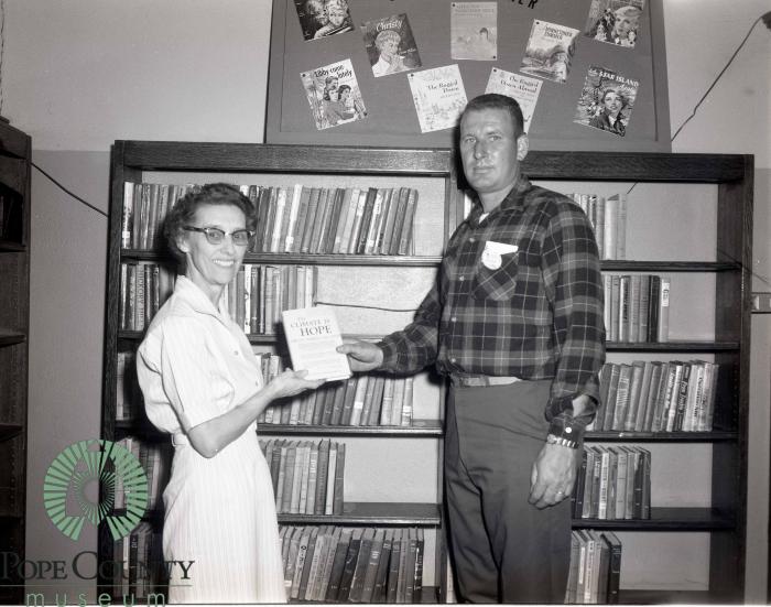 Irene Serrin the Pope county Librarian receiving a book from Bob O'Fallon