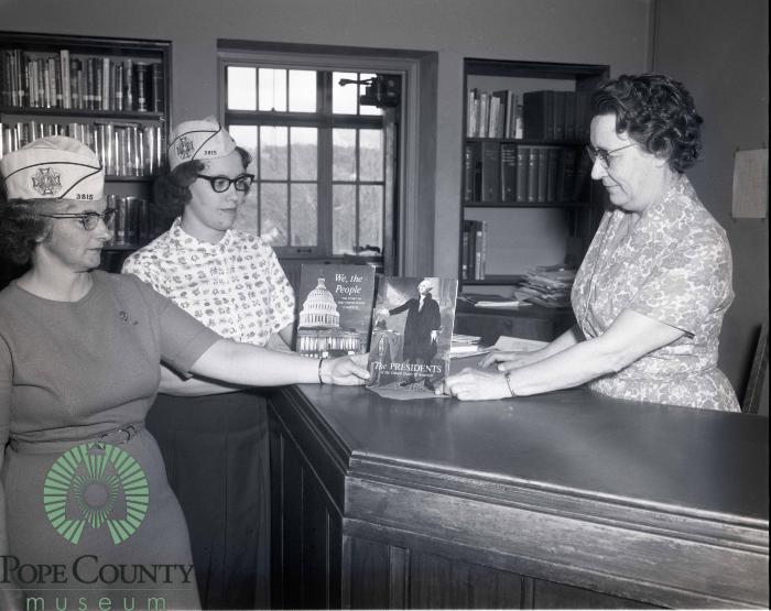 Kathryn Nelson the Central school librarian Receiving books From Minnewaska VFW Auxiliary members Carol Dokken and Donna Hagen