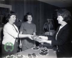 Mrs. Gerald Demars and Martha Rolig handing bread to Maurine Fjoslien