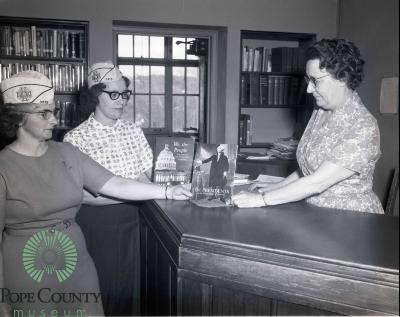 Kathryn Nelson the Central school librarian Receiving books From Minnewaska VFW Auxiliary members Carol Dokken and Donna Hagen