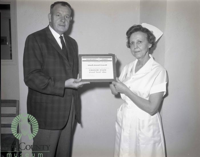 William MacGregor presenting Dina Bremness a Medicare Plaque