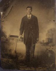 Tintype studio photograph of standing young man in dark suit