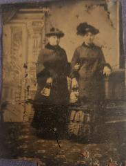 Tintype studio photograph of two women in long dresses