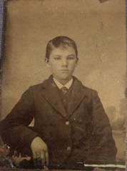 Tintype studio photograph of young man, from the waist up, in dark suit, white shirt and tie
