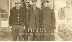 Black and white photograph of 4 men standing on corner in Kasson