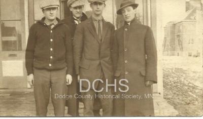 Black and white photograph of 4 men standing on corner in Kasson