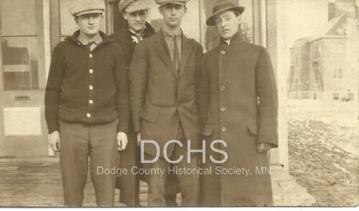 Black and white photograph of 4 men standing on corner in Kasson