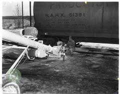 Workman watches elevator take potash from railroad car to warehouse