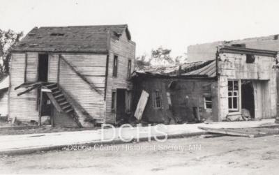 Black and white photograph of several tornado damaged store fronts