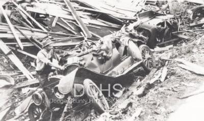 Black and white photograph of man looking at cars damaged by tornado