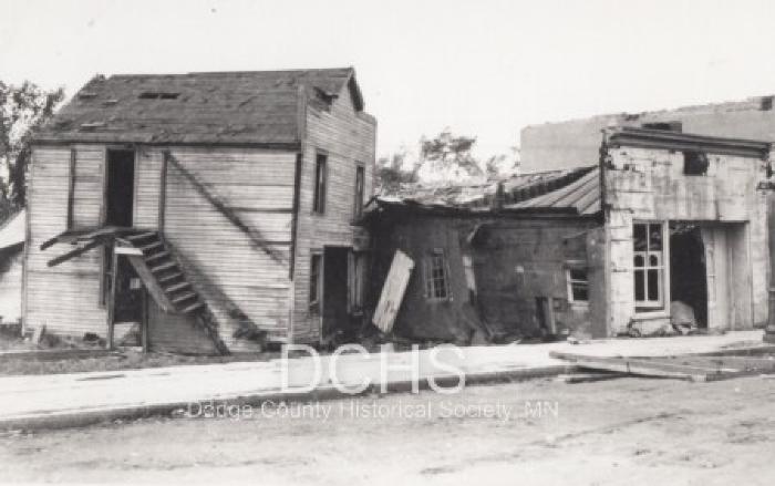 Black and white photograph of several tornado damaged store fronts