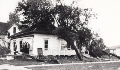 Black and white photograph of house with trees felled on it